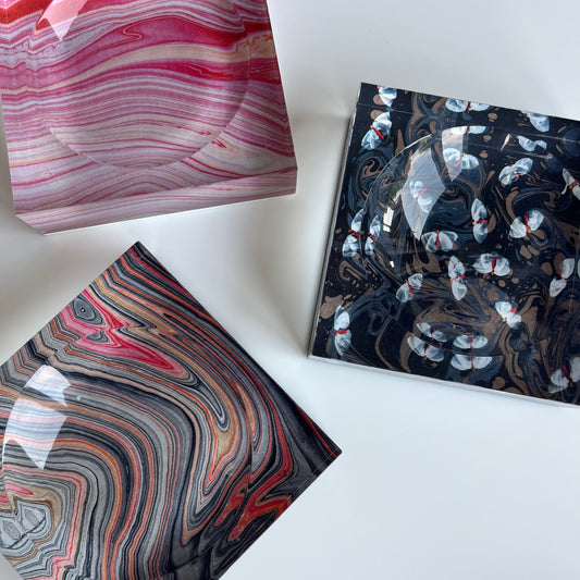 A set of three acrylic candy trays with marbled patterns in pink, black, and red colors.
