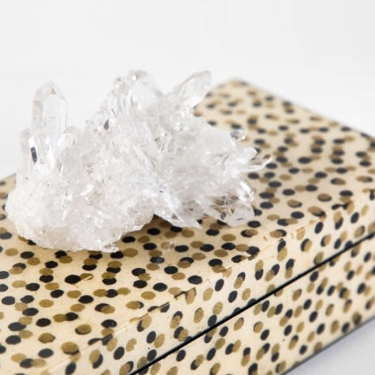 A clear quartz crystal adorns the top of a lacquered box with a dotted pattern, which is open and shows the black felt lining.