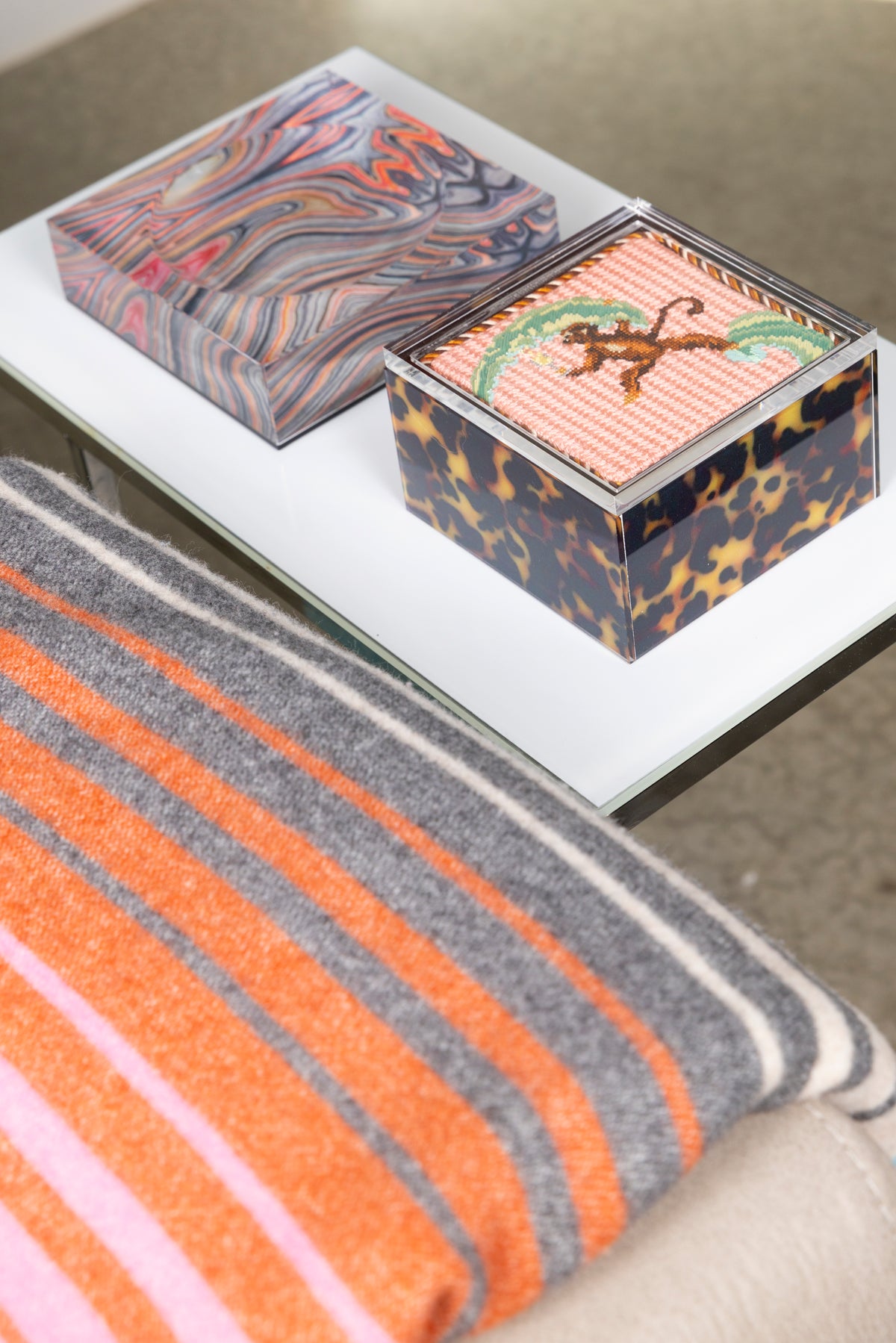 Tortoise acrylic box with finished needlepoint in lifestyle setting with missoni blanket