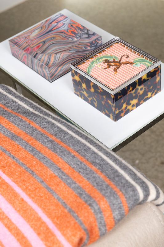 Tortoise acrylic box with finished needlepoint in lifestyle setting with missoni blanket
