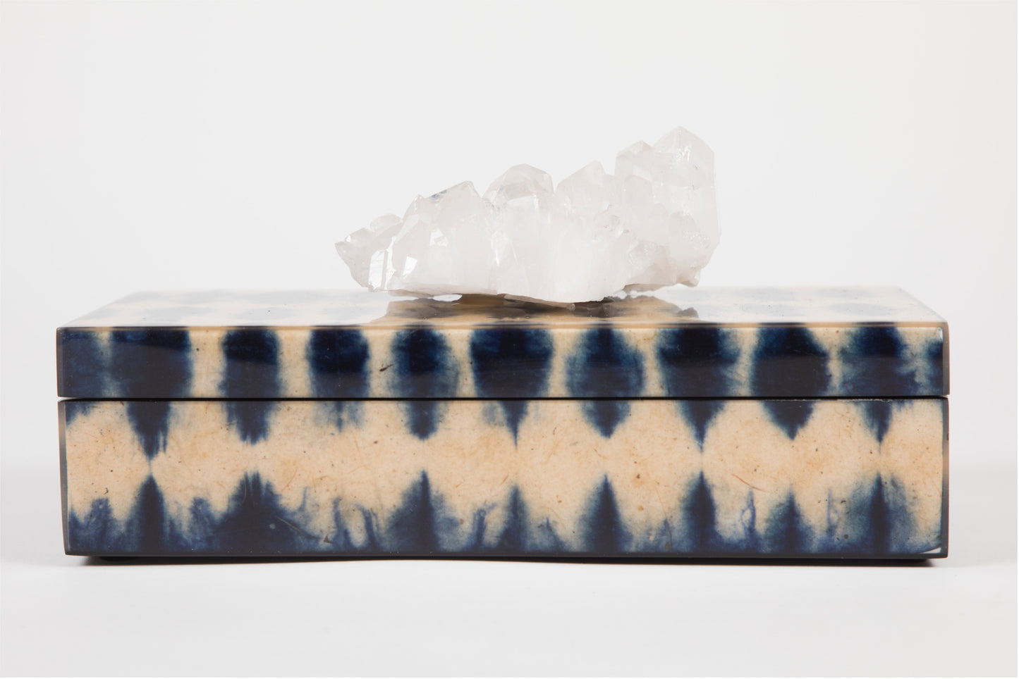 A closed blue ikat pencil box with a semi precious crystal topper on top, displaying a geometric pattern.