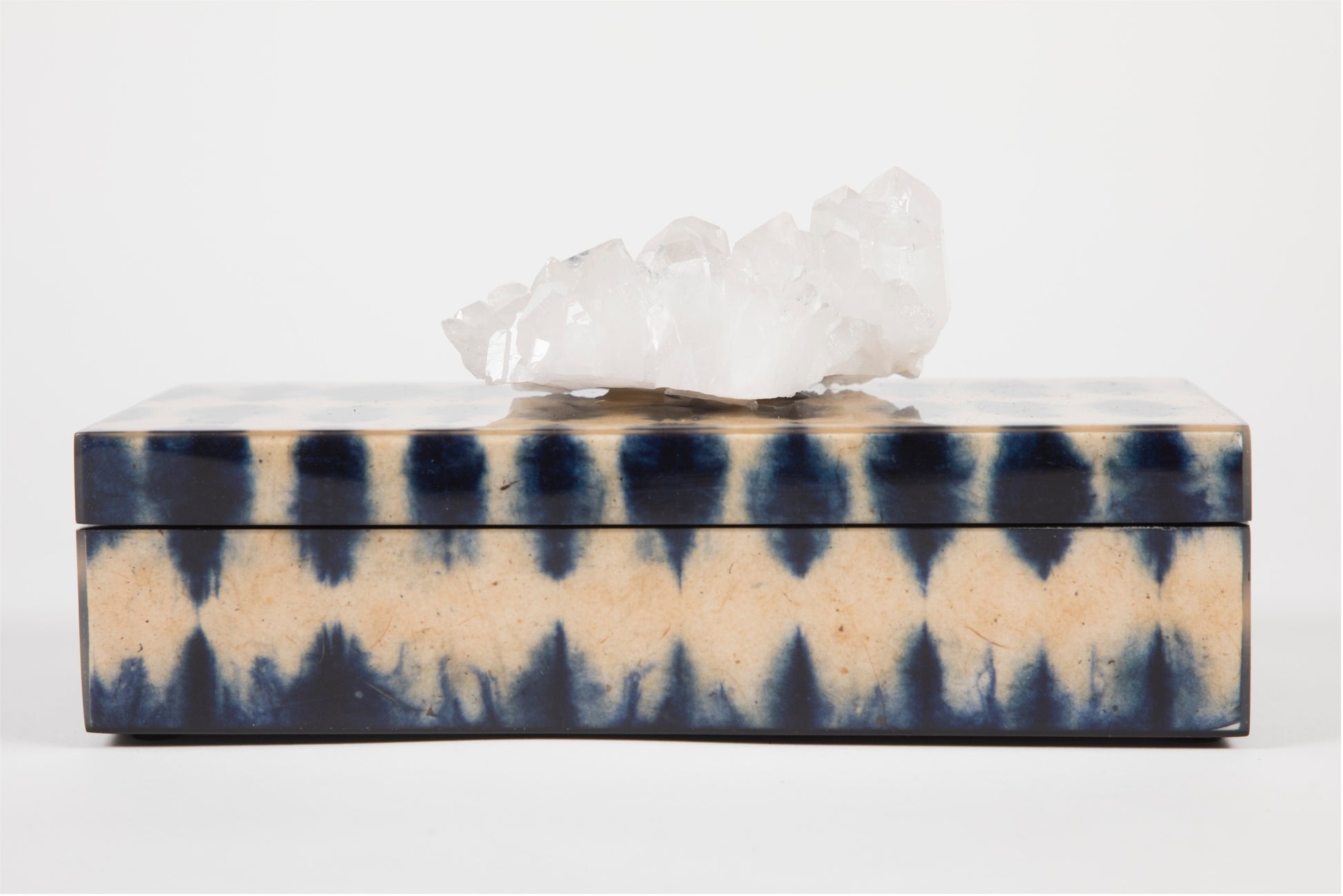 A closed blue ikat pencil box with a semi precious crystal topper on top, displaying a geometric pattern.