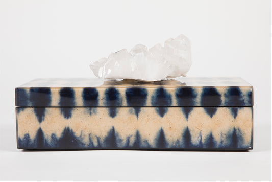 A closed blue ikat pencil box with a semi precious crystal topper on top, displaying a geometric pattern.