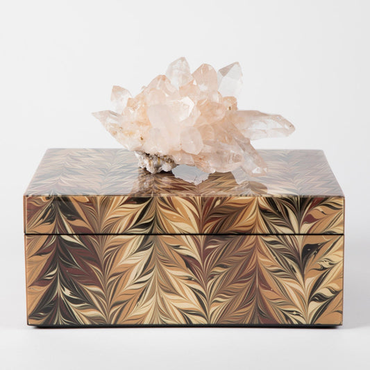 A decorative lacquer box with a geometric pattern, topped with a semi-precious crystal, providing a unique and luxurious gift option.