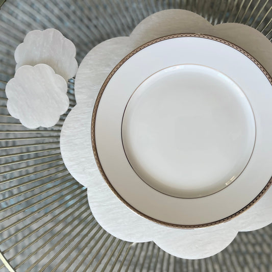 A set of four white scalloped coasters with  white scallop placemat and dinner plate
