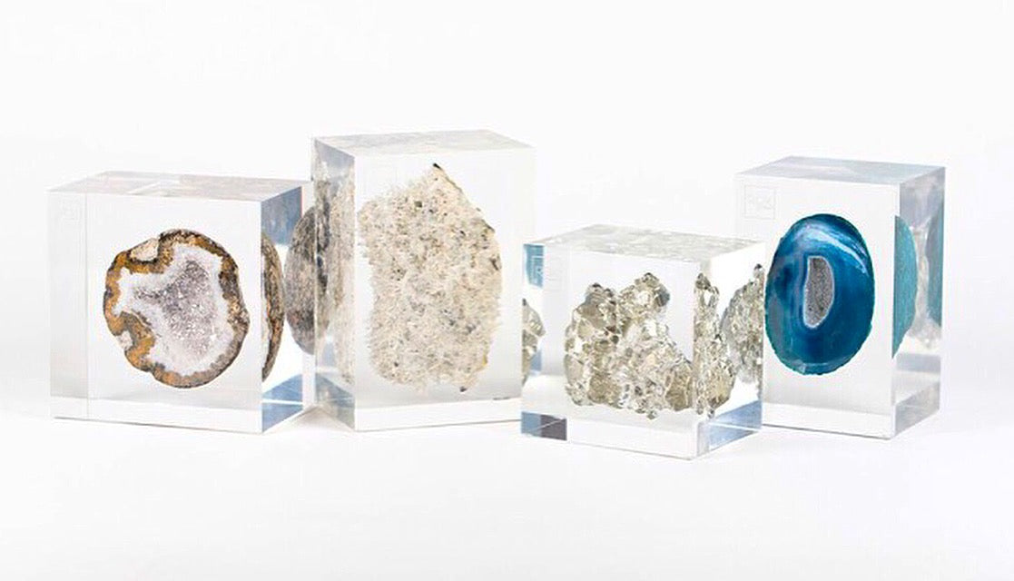 A collection of clear acrylic embedments containing different types of crystals, displayed in three square blocks.