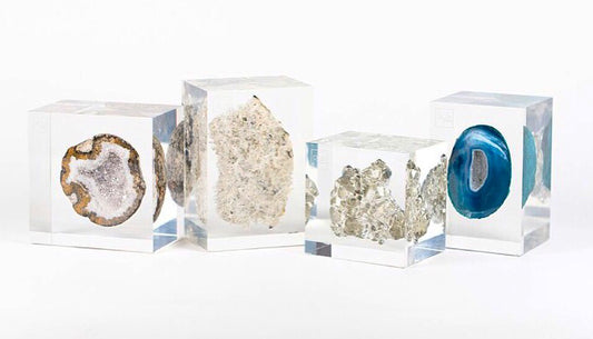 A collection of clear acrylic embedments containing different types of crystals, displayed in three square blocks.